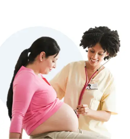 A Female doctor listens with a stethoscope on a pregnant woman's belly