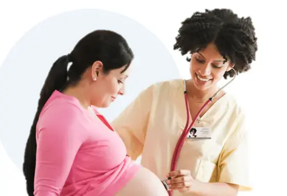 A Female doctor listens with a stethoscope on a pregnant woman's belly